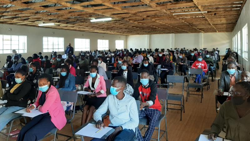 Young people sitting in a big room taking an exam